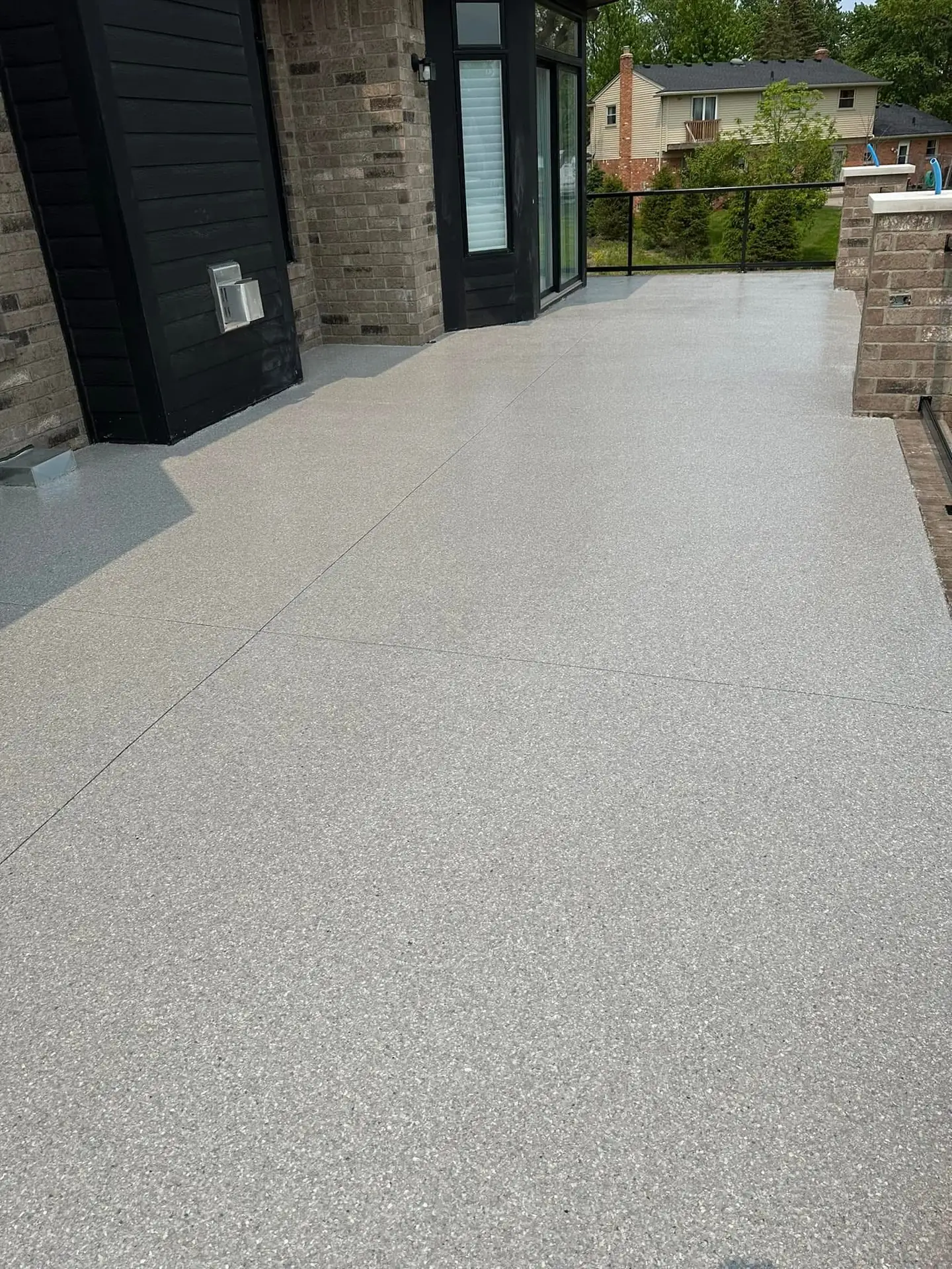 Light grey textured floor coating on an outdoor terrace beside a home